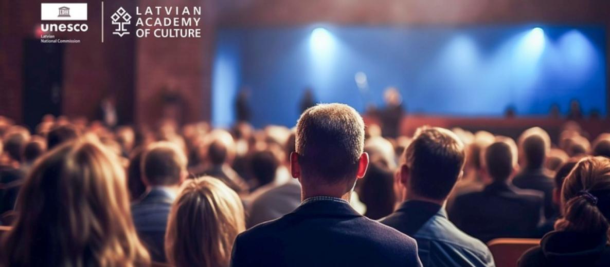 Widownia na konferencji; scena w niebieskim świetle; logotypy UNESCO Latvia i Latvian Academy of Culture.
